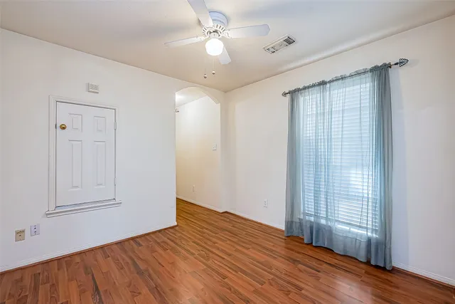 a view of an empty room with wooden floor and a window