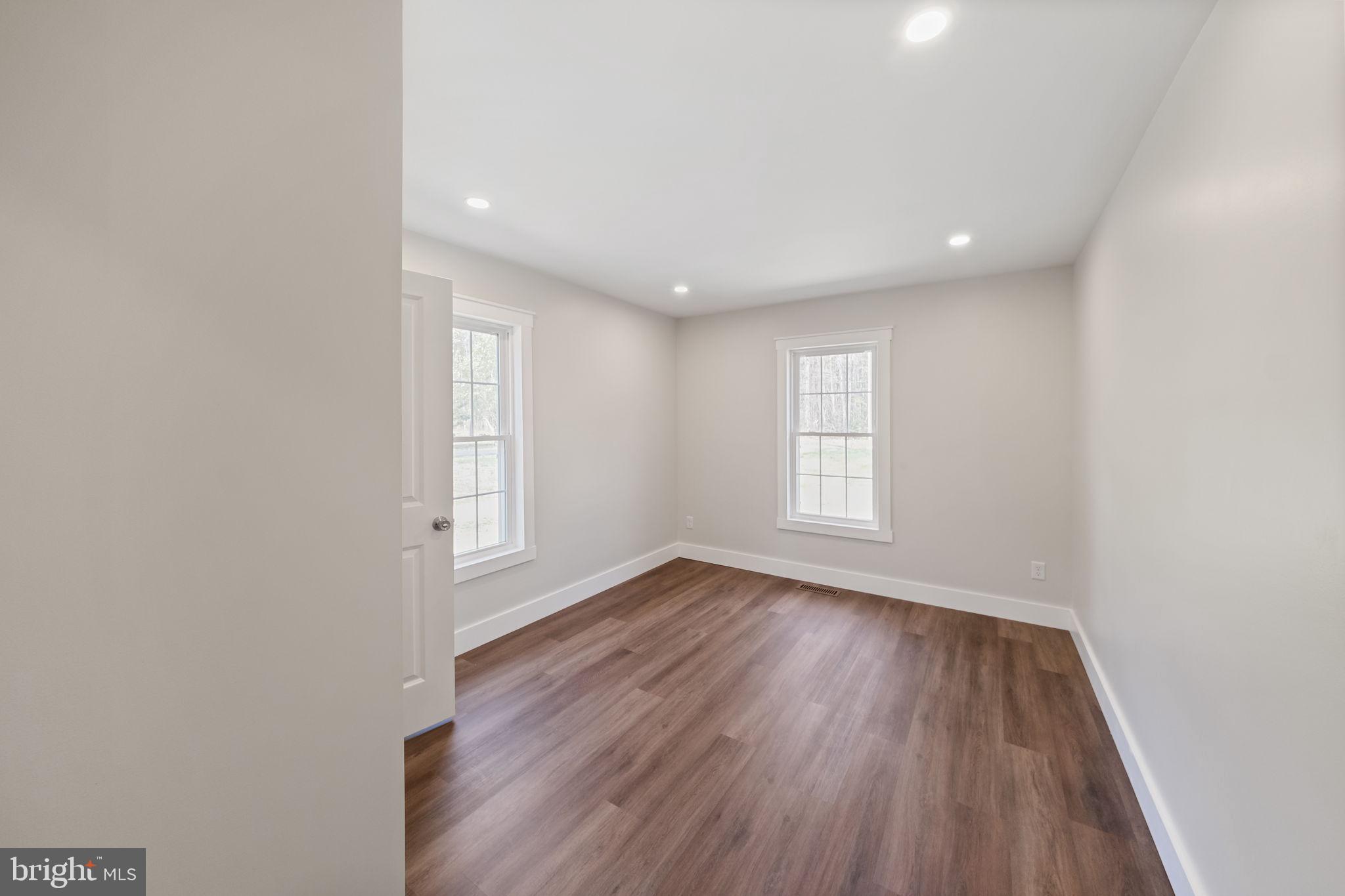 646 Sandy Point Road Heathsville, VA 22473 - Photo 20 of 39 an empty room with wooden floor and windows