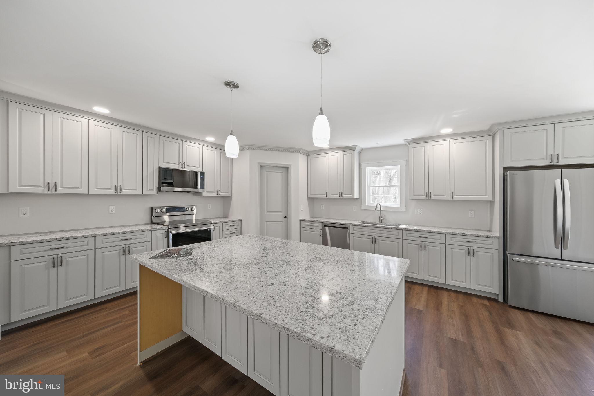 646 Sandy Point Road Heathsville, VA 22473 - Photo 10 of 39 a kitchen with stainless steel appliances granite countertop a refrigerator a sink dishwasher a stove and white countertops with wooden floor