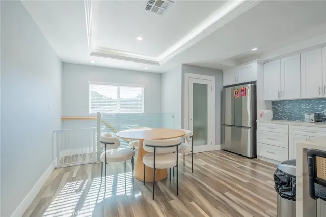 a kitchen with stainless steel appliances granite countertop a stove a refrigerator a sink a dining table and chairs with wooden floor