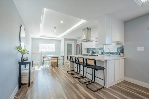 a kitchen with granite countertop a stove and white cabinets with wooden floor