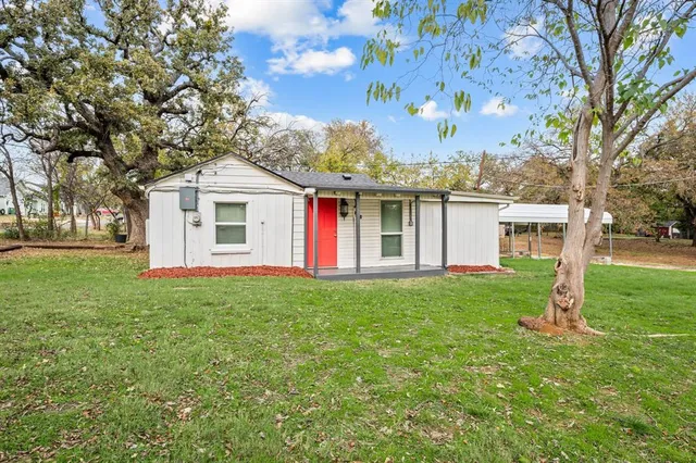 a view of a yard in front of a house with plants and large tree