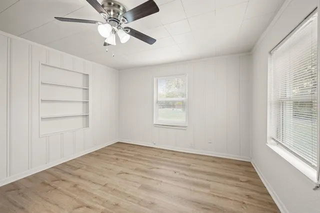an empty room with windows and fan