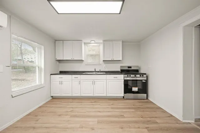 a kitchen with granite countertop a stove a sink and a microwave