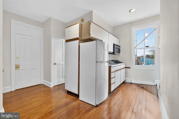 a kitchen with white cabinets and wooden floor