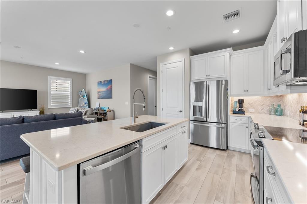 2609 Seychelles Circle, Unit 1608 Naples, FL 34112 - Photo 11 of 35 a kitchen with a sink a refrigerator and a stove top oven with wooden floor