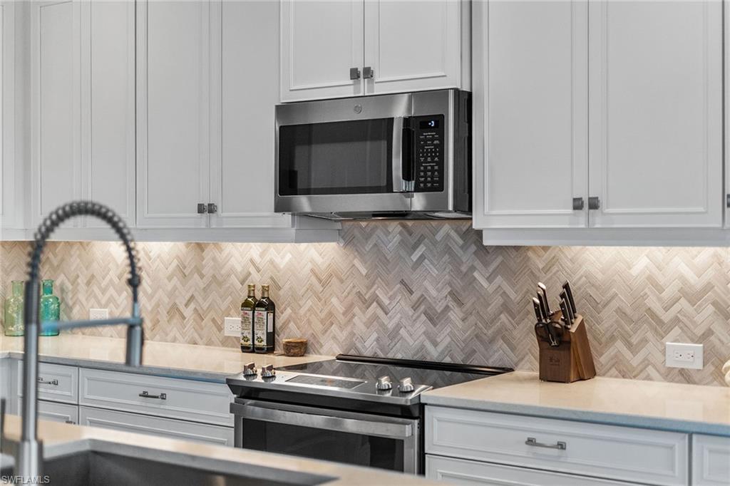 2609 Seychelles Circle, Unit 1608 Naples, FL 34112 - Photo 14 of 35 a kitchen with granite countertop white cabinets and black appliances