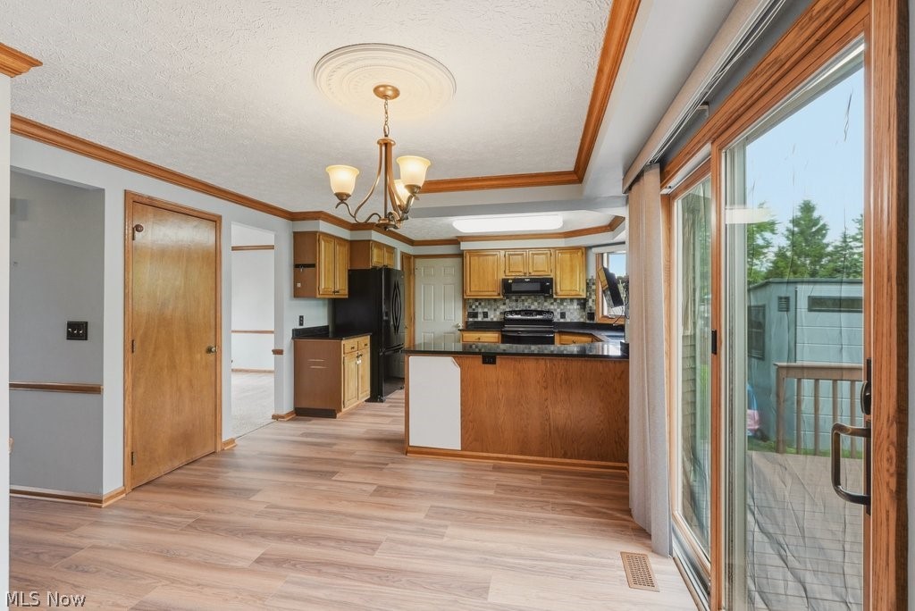 5321 Young Road Stow, OH 44224 - Photo 11 of 37 Open-concept kitchen and dining area featuring wood-finish flooring, a decorative ceiling medallion with a chandelier, and a kitchen island with a dark countertop