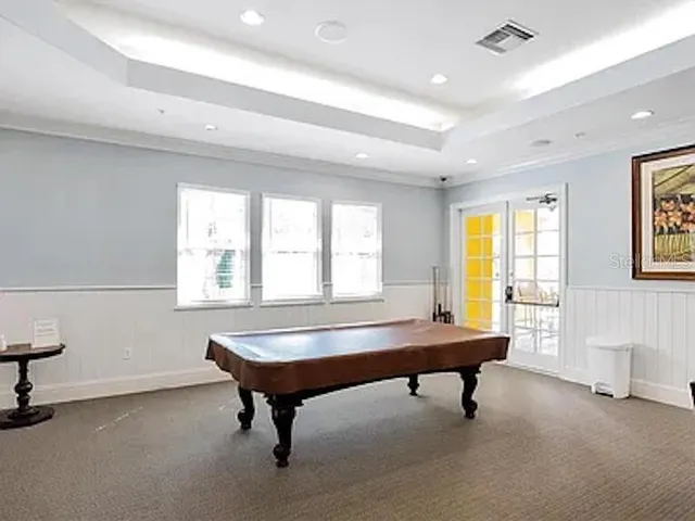 a room with pool table and windows
