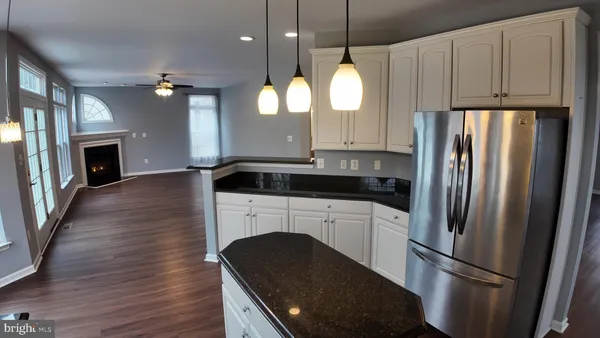 a kitchen with granite countertop a refrigerator a oven and a sink with wooden floor