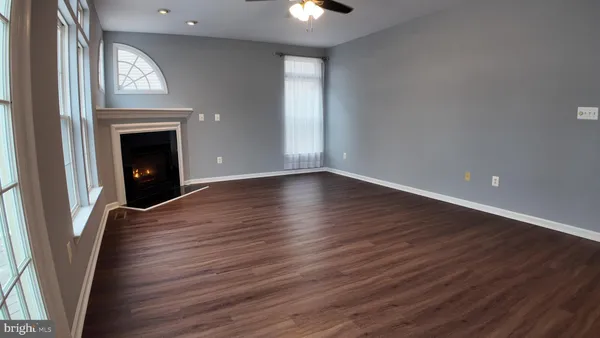an empty room with wooden floor fireplace and windows