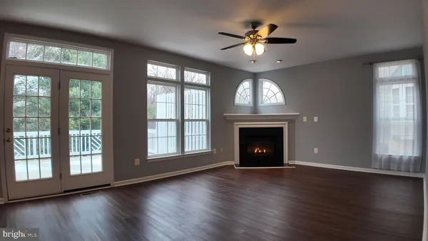 a view of an empty room with wooden floor fireplace and a window