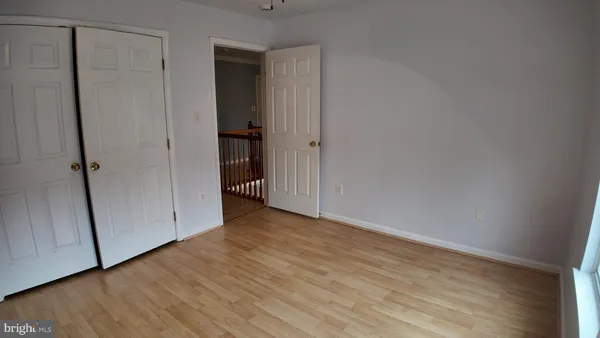 a view of an empty room with wooden floor and closet