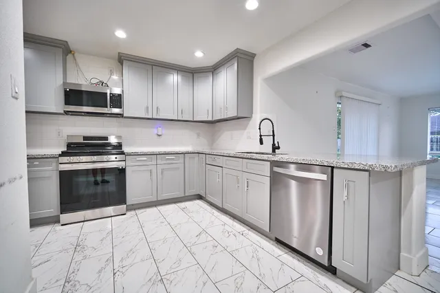 a kitchen with stainless steel appliances granite countertop a sink and dishwasher a refrigerator with wooden cabinets