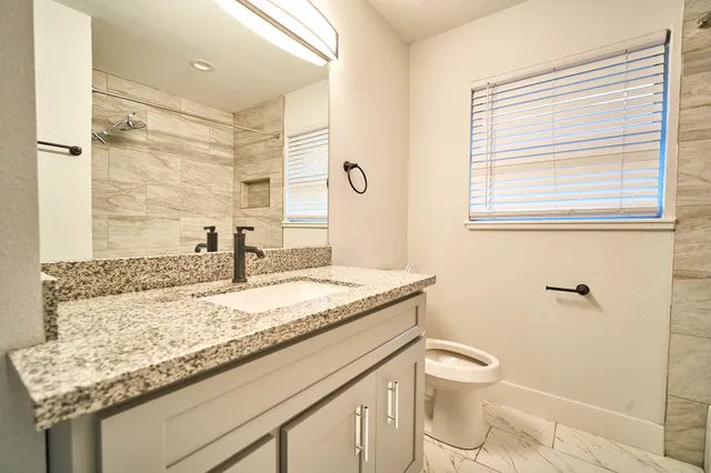 a bathroom with a granite countertop sink toilet and shower
