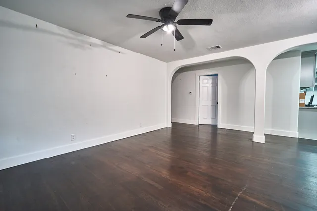 an empty room with wooden floor and fan