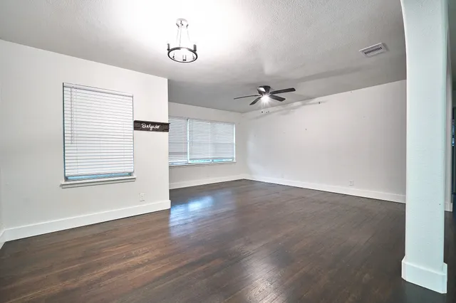 a view of an empty room with a window and wooden floor