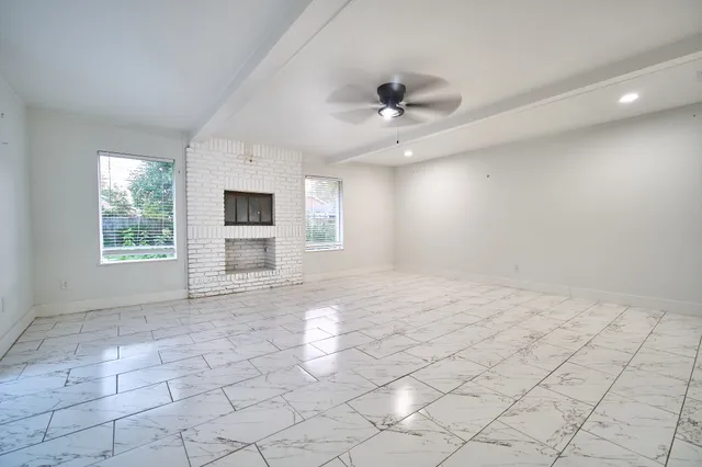 an empty room with windows and fireplace
