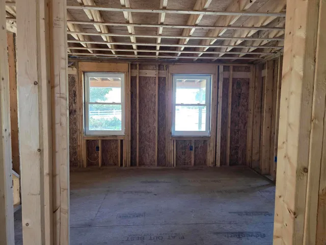 a view of an empty room with wooden floor and windows