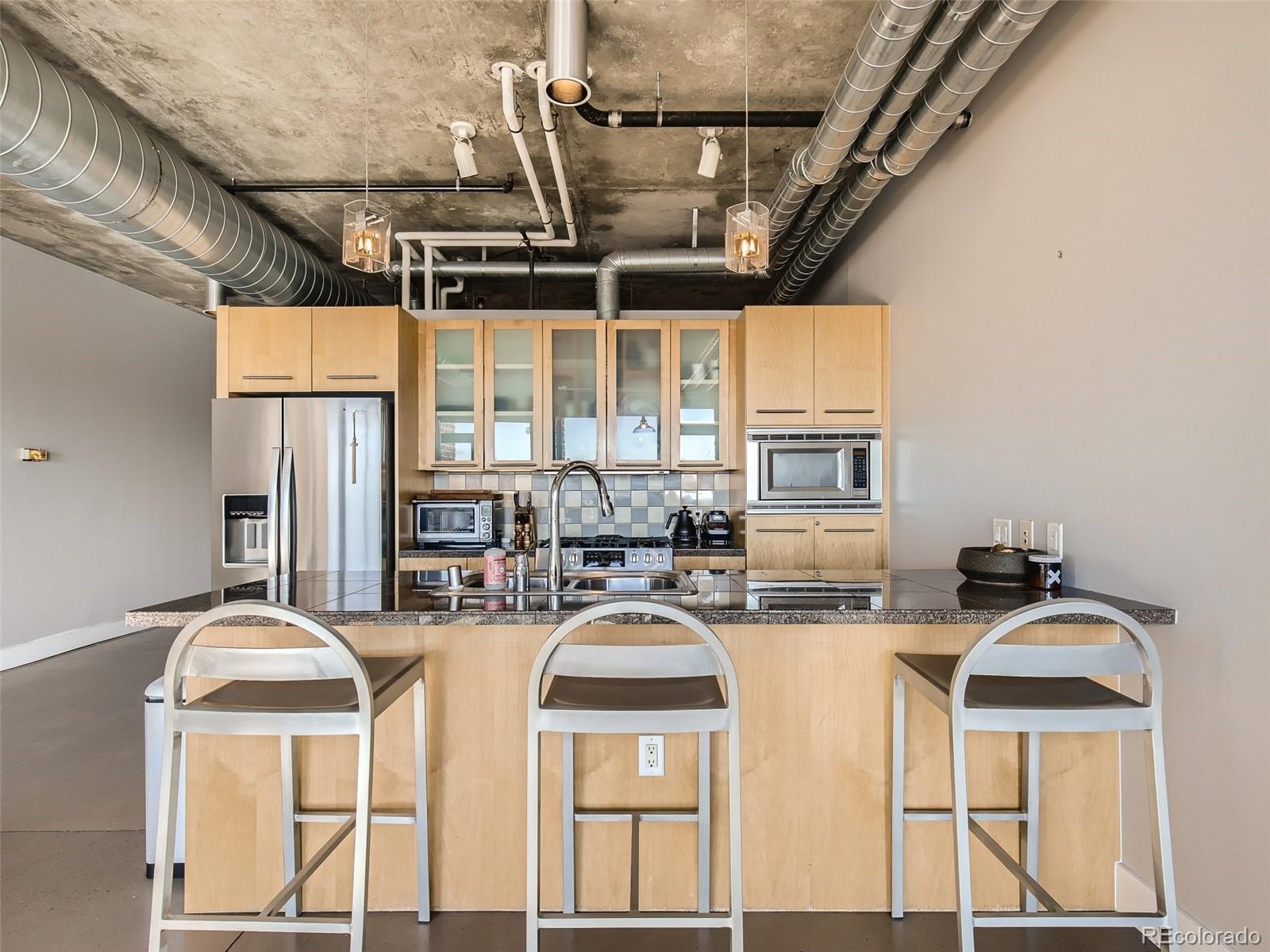 2100 16th St Mall, Unit 604 Denver, CO 80202 - Photo 6 of 20 a kitchen with stainless steel appliances granite countertop a stove a refrigerator a sink dishwasher a dining table and chairs with wooden floor