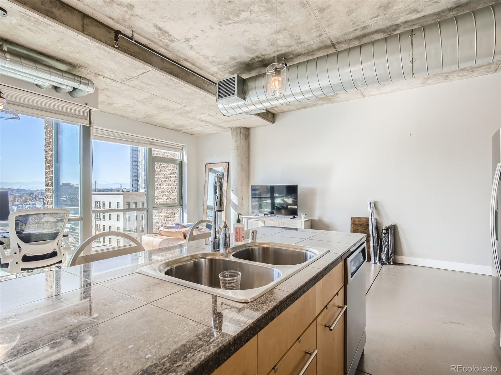 2100 16th St Mall, Unit 604 Denver, CO 80202 - Photo 9 of 20 a kitchen with a sink a counter top space and living room filled with furniture
