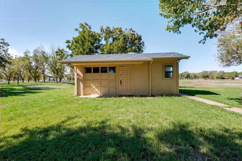 8105 Ravenswood Road Granbury, TX 76049 - Photo 21 of 28 Detached structure featuring a paneled garage door, side entry door, and a single window