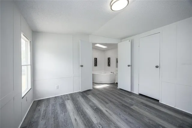 a view of a room with wooden floor white walls and windows
