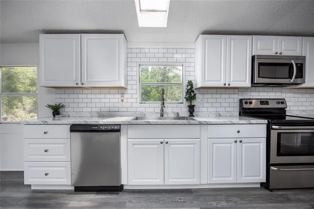 a kitchen with white cabinets and sink
