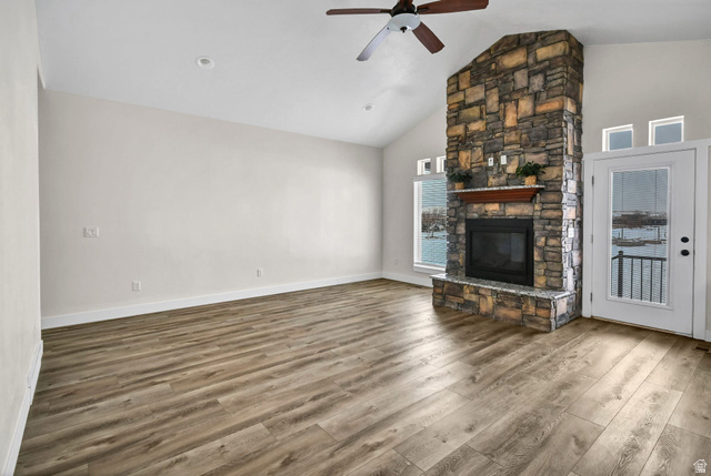 1103 North Brooklyn Road Monroe, UT 84754 - Photo 15 of 78 Unfurnished living room featuring a stone fireplace, a ceiling fan, wood finished floors, and high vaulted ceiling