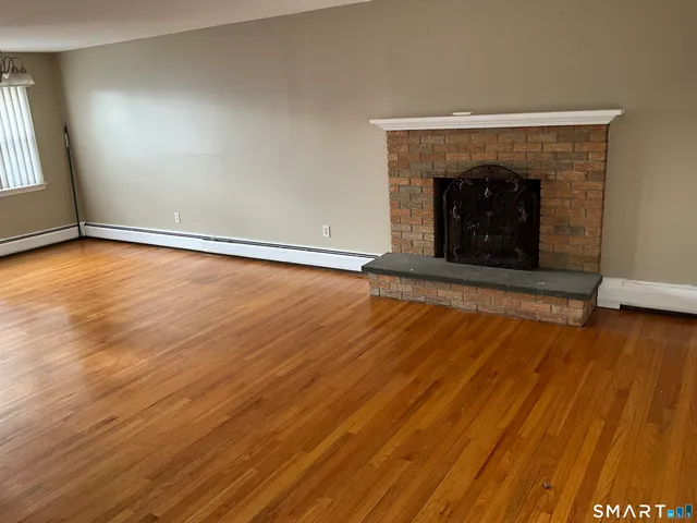 an empty room with wooden floor and fireplace