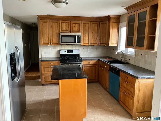 a kitchen with stainless steel appliances granite countertop a stove a sink and a microwave