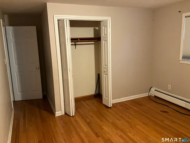 an empty room with wooden floor and a bathroom