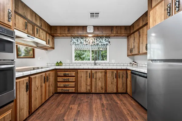 a kitchen with stainless steel appliances granite countertop a stove a sink and a refrigerator