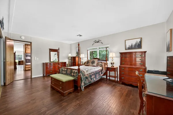a spacious bedroom with a bed and wooden floor