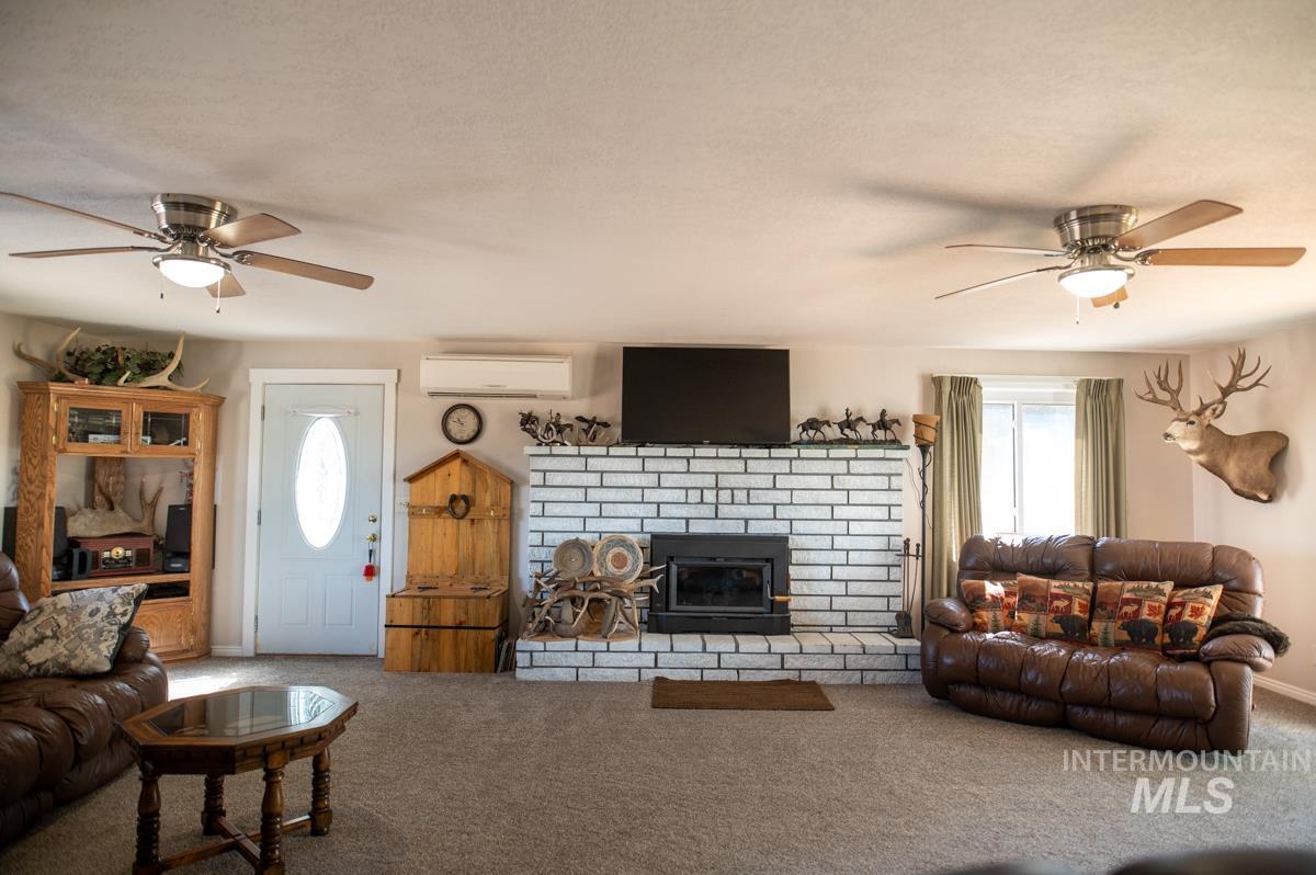 733 Pringle Road Weiser, ID 83672 - Photo 12 of 46 Carpeted living room featuring a ceiling fan, a fireplace, and a wall mounted air conditioner