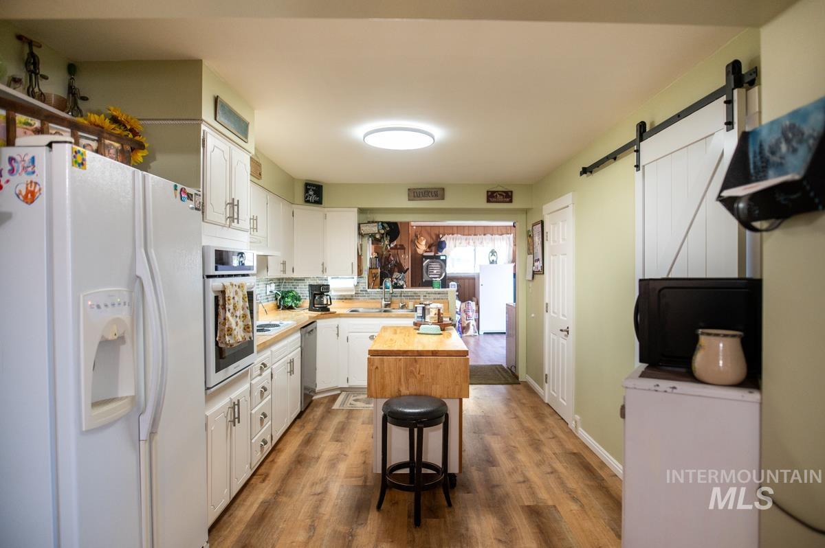 733 Pringle Road Weiser, ID 83672 - Photo 14 of 46 Kitchen with stainless steel appliances, white cabinetry, a barn door, and dark wood-style flooring