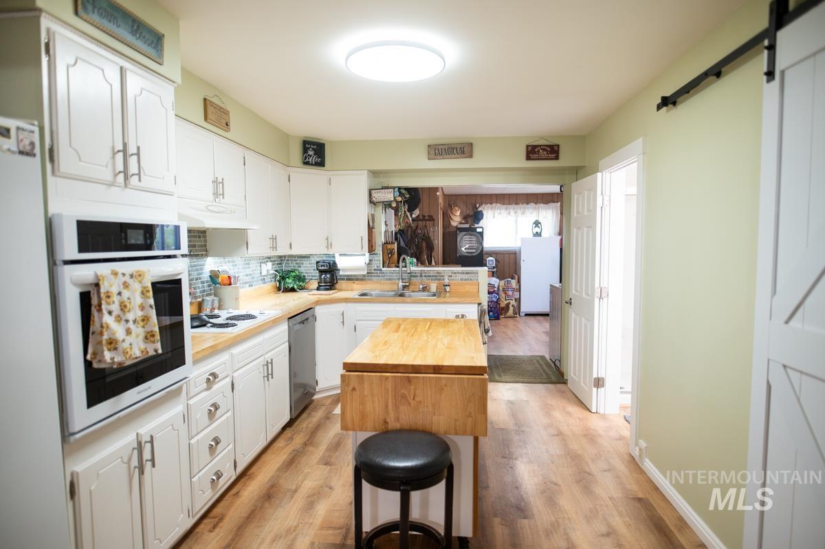 733 Pringle Road Weiser, ID 83672 - Photo 21 of 46 Kitchen featuring a barn door, wood counters, white cabinets, and white appliances