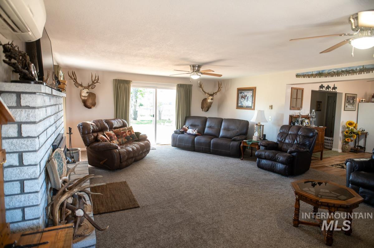 733 Pringle Road Weiser, ID 83672 - Photo 10 of 46 Living area with a wall unit AC, carpet floors, a fireplace, and ceiling fan
