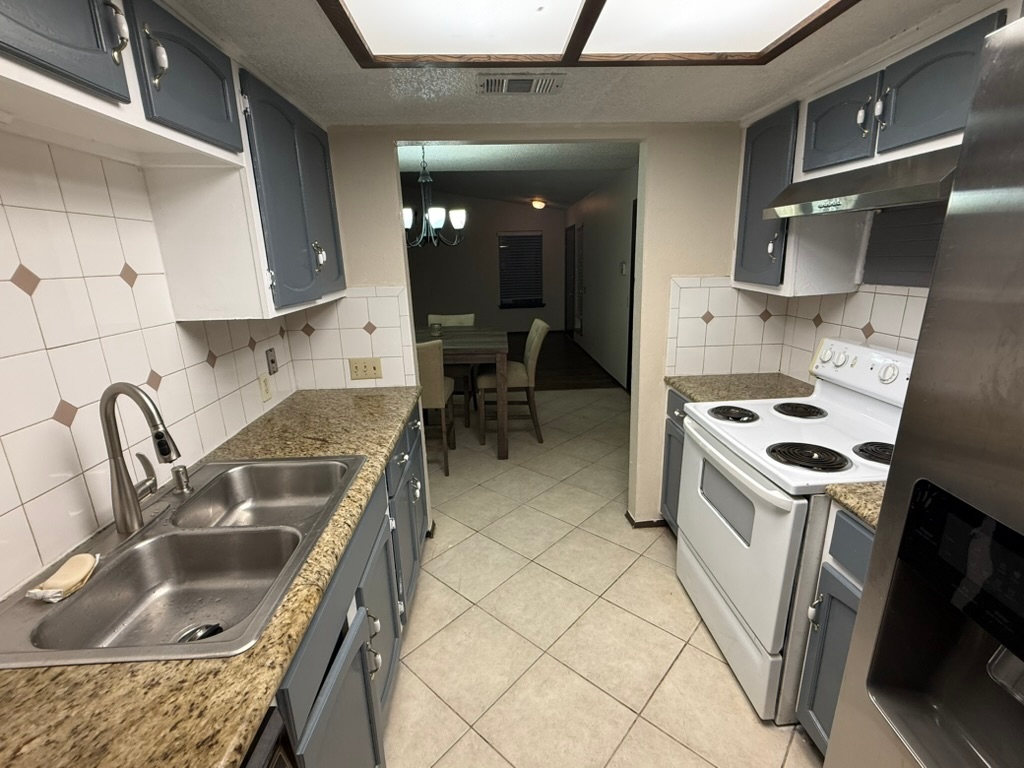 907 East Meadowmere Lane Austin, TX 78758 - Photo 9 of 23 a kitchen with granite countertop a sink a stove and a refrigerator