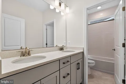 a bathroom with a granite countertop sink a toilet and a mirror