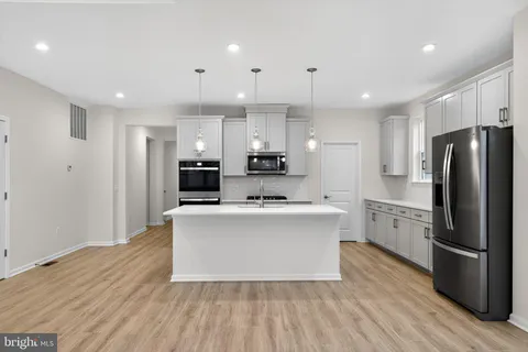 a large kitchen with stainless steel appliances a large counter top and a refrigerator