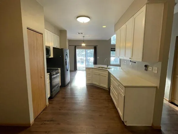 a kitchen with stainless steel appliances a sink a stove top oven a refrigerator and cabinets
