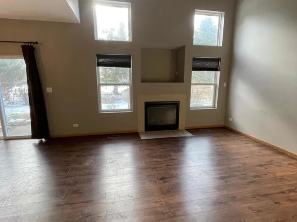 an empty room with wooden floor a fireplace and windows