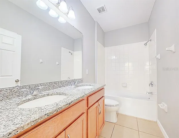 a bathroom with a granite countertop sink a toilet and shower