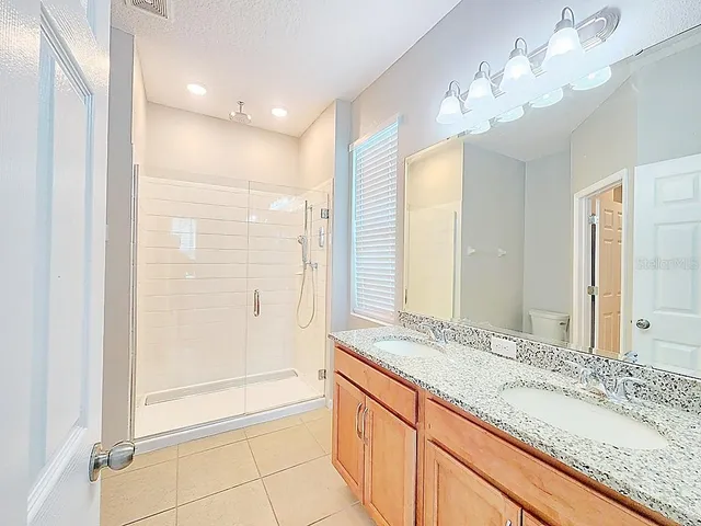 a bathroom with a granite countertop sink a large mirror and a shower