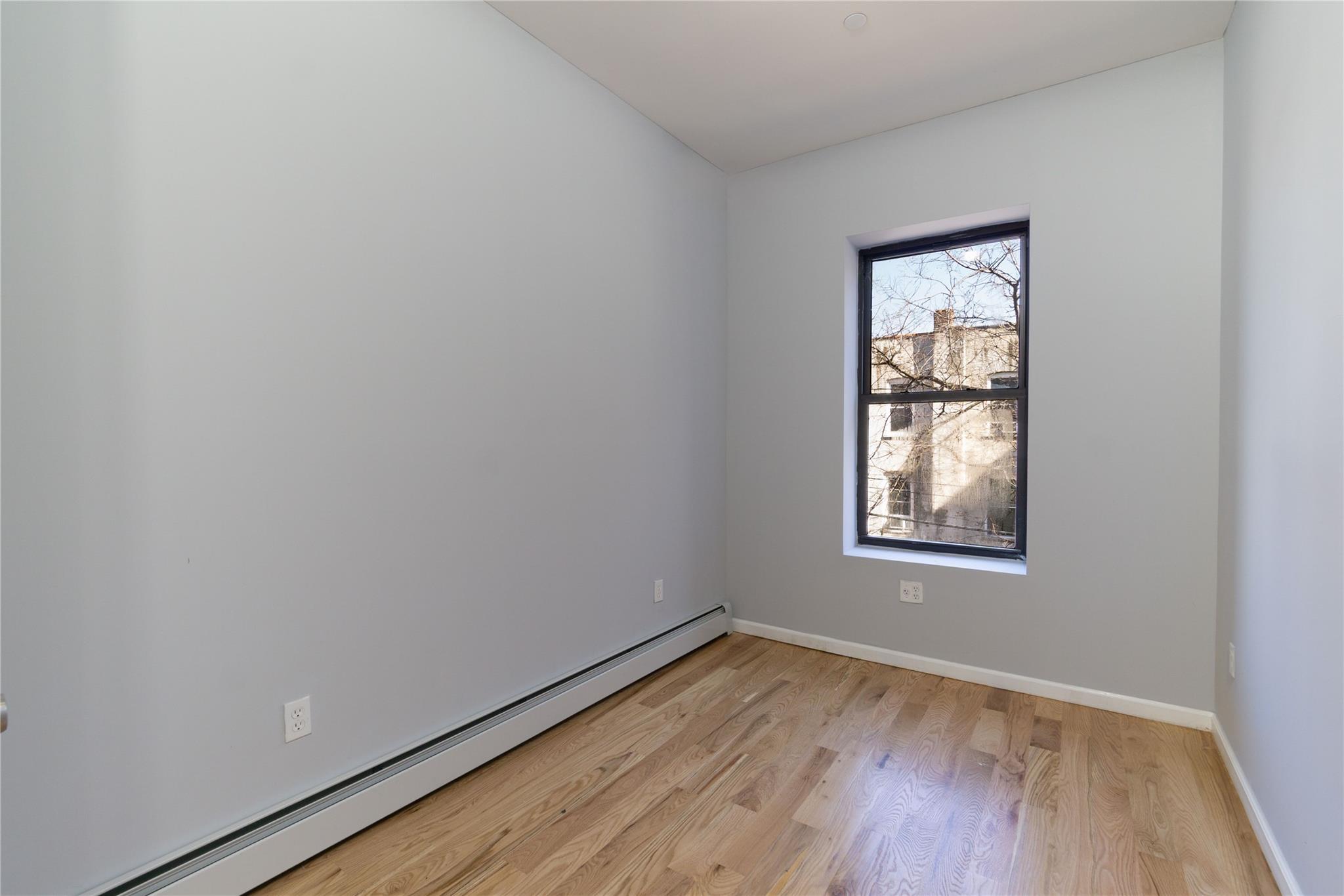 1102 Jackson Avenue Bronx, NY 10456 - Photo 17 of 36 an empty room with wooden floor and windows