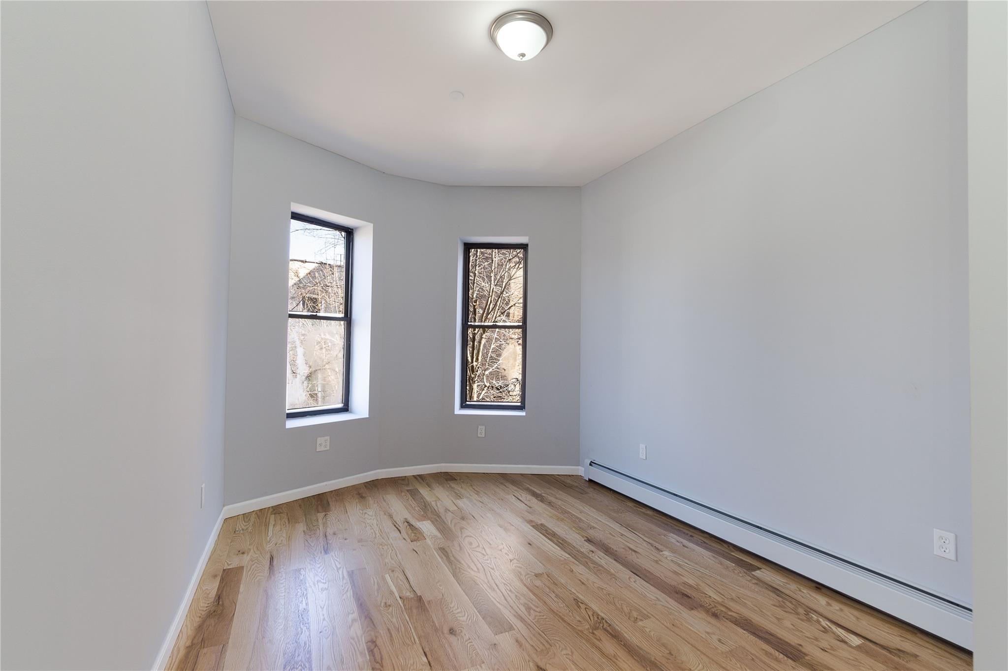 1102 Jackson Avenue Bronx, NY 10456 - Photo 19 of 36 an empty room with wooden floor and windows