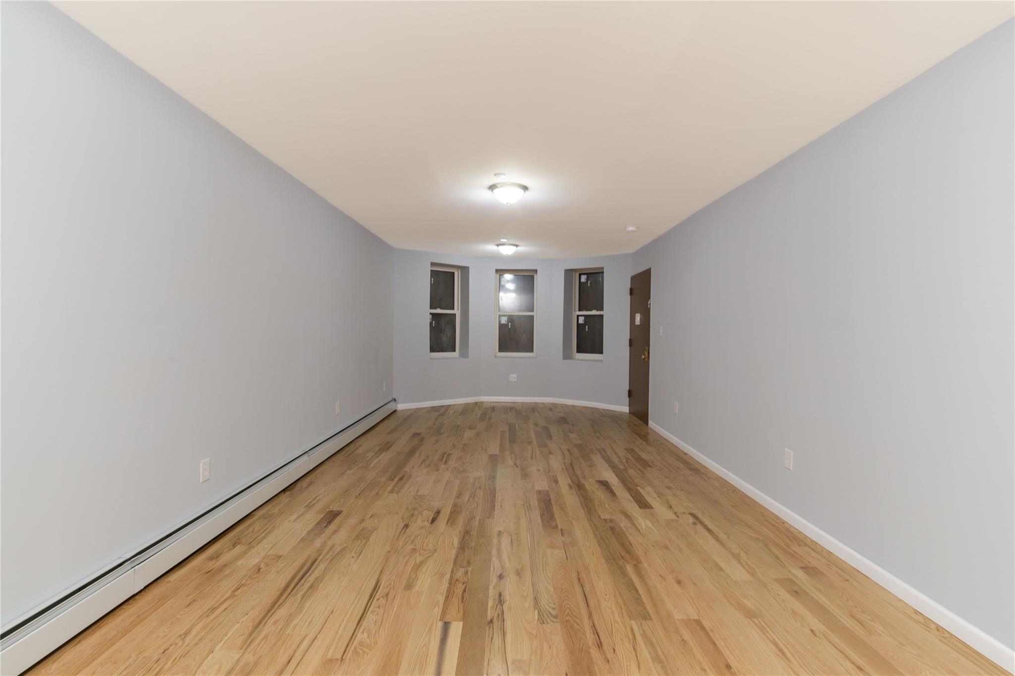 1102 Jackson Avenue Bronx, NY 10456 - Photo 27 of 36 a view of an empty room with wooden floor and a window