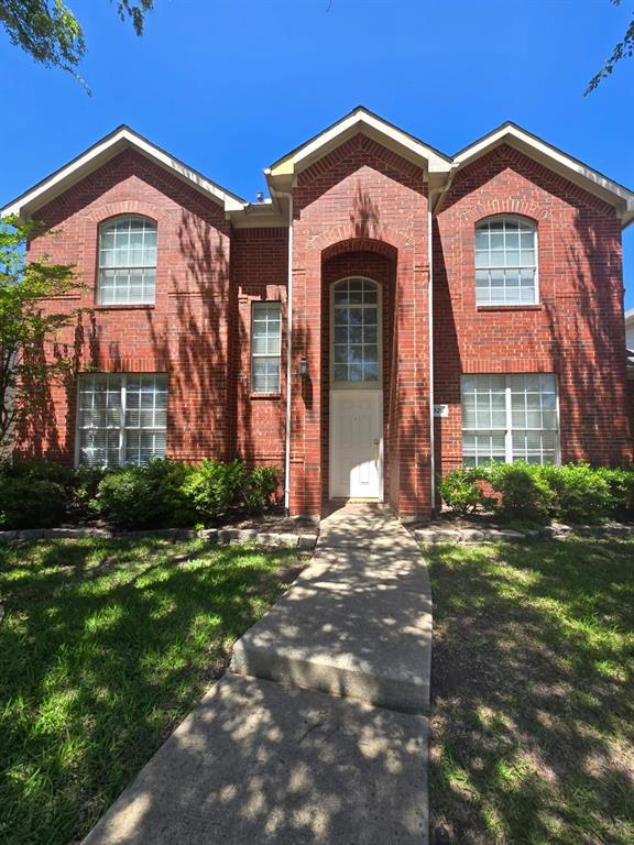 View of front facade featuring brick siding and a front yard