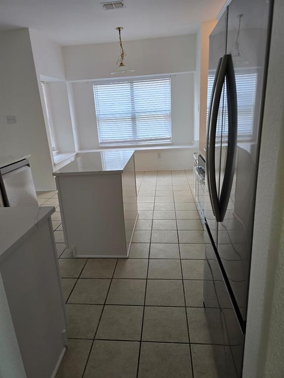 4325 Ridge Point Lane Plano, TX 75024 - Photo 9 of 11 Kitchen with light tile patterned flooring, visible vents, light countertops, hanging light fixtures, and freestanding refrigerator